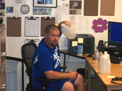 Male staff member sitting at desk holding  half gallon bottle water